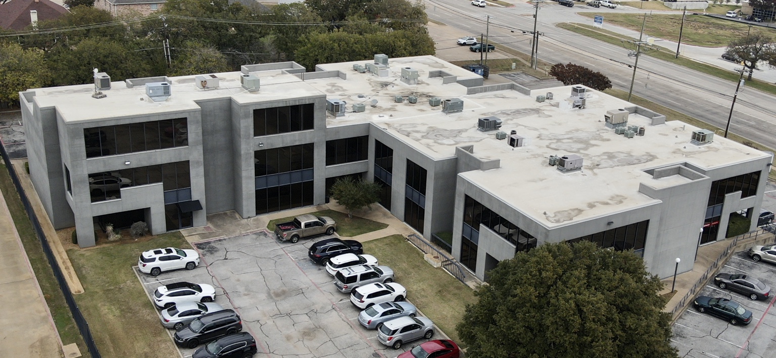 Aerial view of a commercial building with roof equipment and parking
